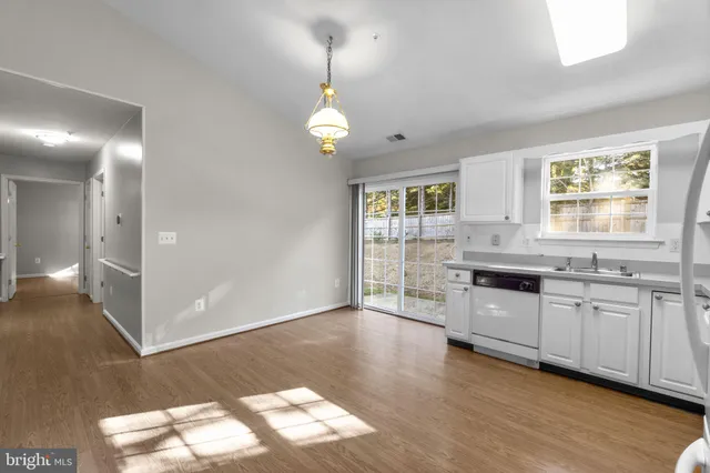 a large kitchen with granite countertop a stove a sink a window and wooden floor