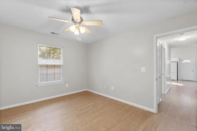 an empty room with windows and fan