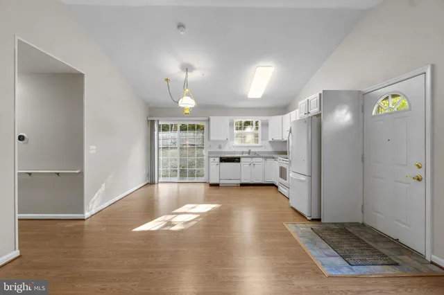 a view of an empty room with kitchen and window