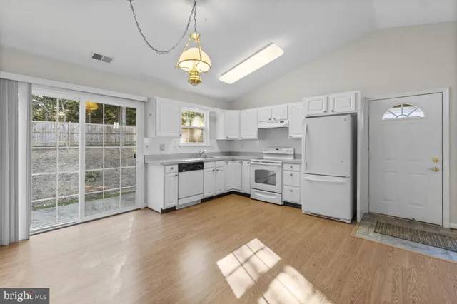 a kitchen with stainless steel appliances granite countertop a refrigerator a stove a sink dishwasher a dining table and chairs with wooden floor