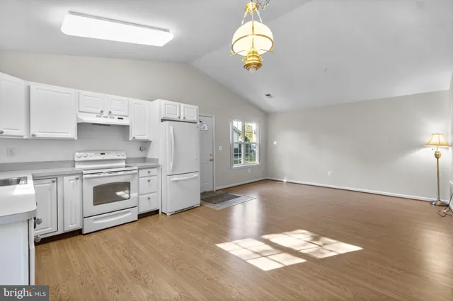 a kitchen with granite countertop a stove cabinets and wooden floor