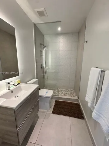 a bathroom with a sink a toilet a mirror and shower