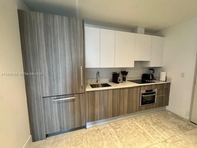 a kitchen with granite countertop a sink cabinets and stainless steel appliances