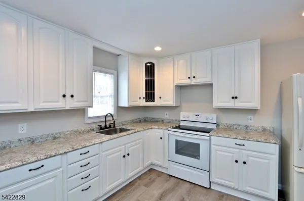 a kitchen with granite countertop white cabinets and white appliances