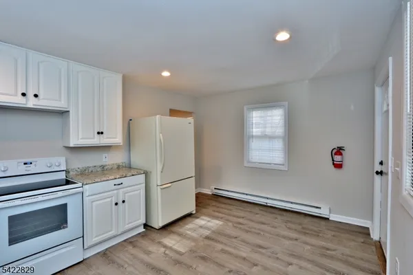 a kitchen with granite countertop white cabinets and white appliances