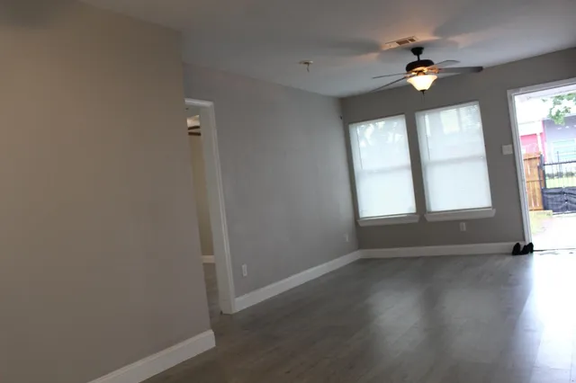 an empty room with wooden floor and windows
