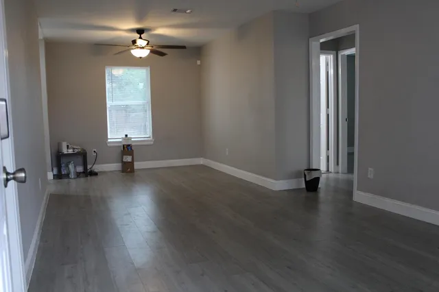 an empty room with wooden floor and windows