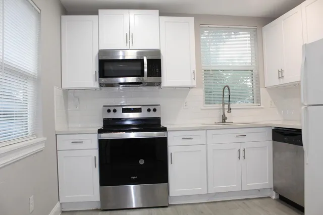 a kitchen with white cabinets stainless steel appliances and sink