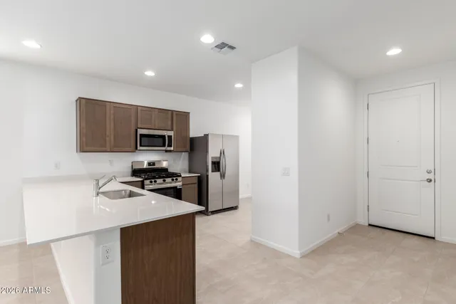 a kitchen with stainless steel appliances a refrigerator a stove top oven a sink and cabinets