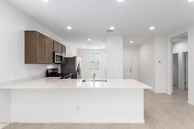 a large white kitchen with kitchen island a sink stainless steel appliances and cabinets