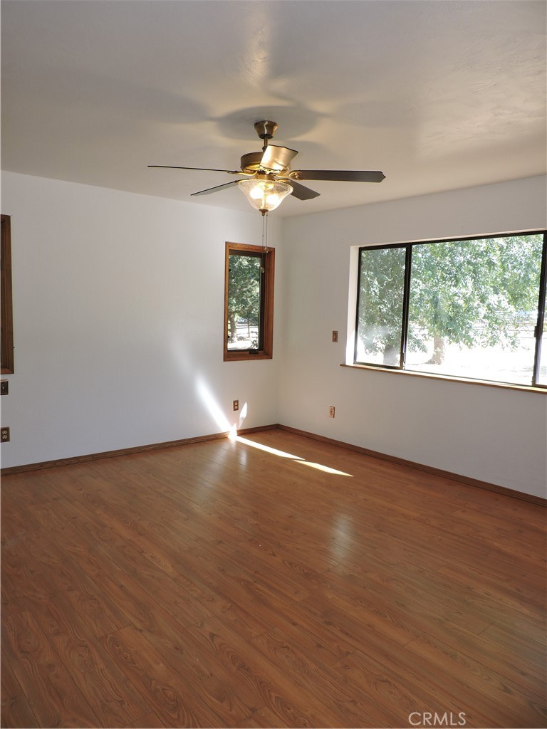 26931 Columbia Way Tehachapi, CA 93561 - Photo 44 of 49 Primary Bedroom has wood flooring, new interior paint, new ceiling fan and plenty of windows with natural light. Amazing mountain views!