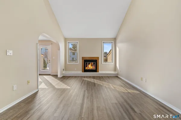 an empty room with wooden floor fireplace and windows