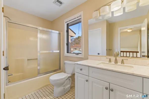 a bathroom with a granite countertop sink toilet a large mirror a shower and a bathtub