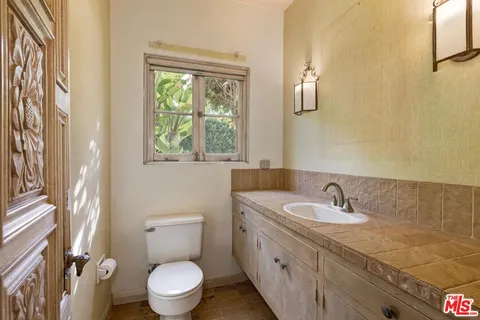 a bathroom with a sink toilet a mirror and a window