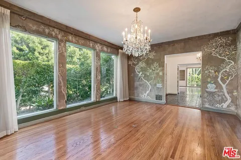 a view of a livingroom with wooden floor a chandelier and windows