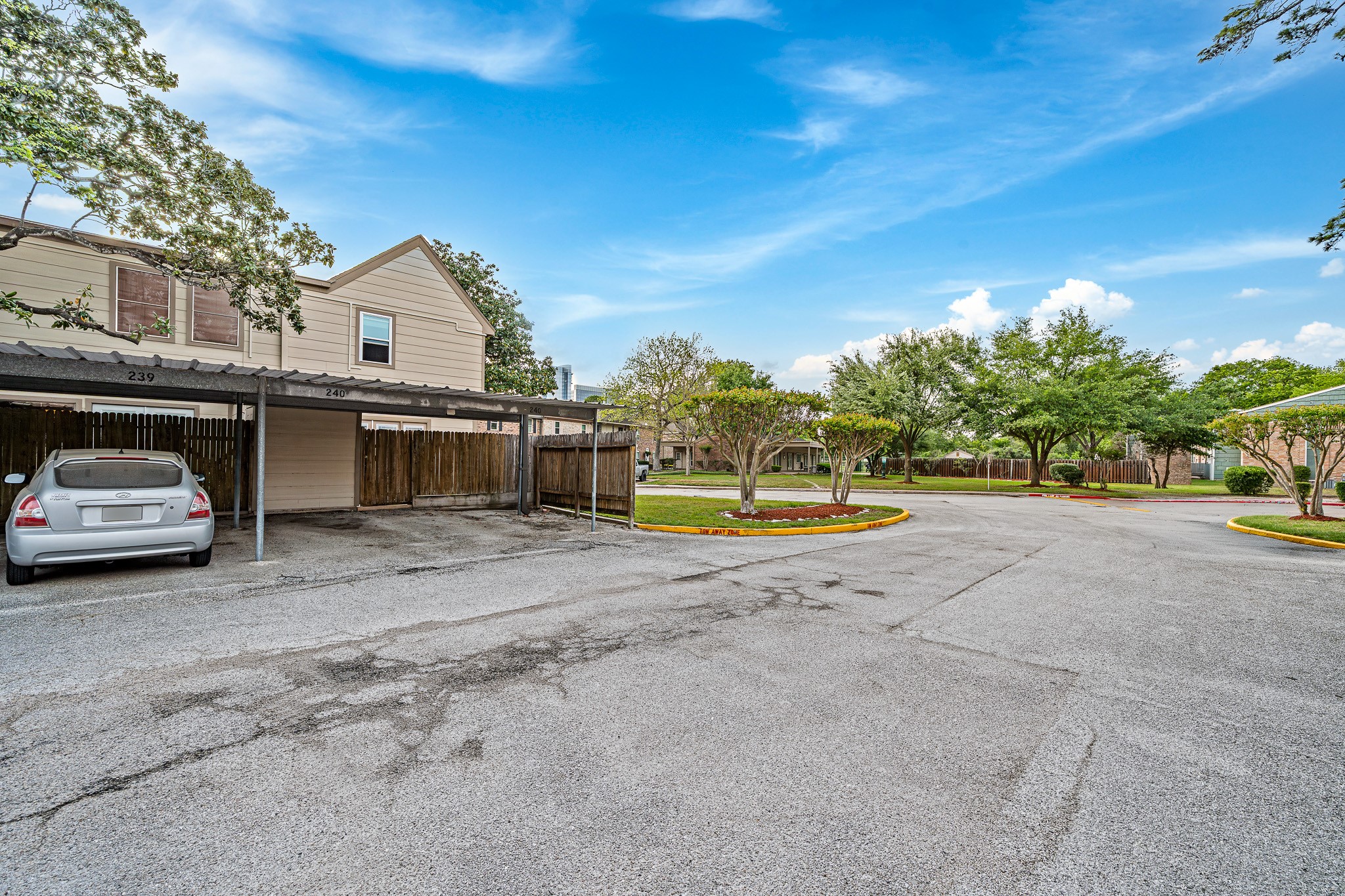 830 Threadneedle Street, Unit 240 Houston, TX 77079 - Photo 29 of 33 This photo shows a residential area with covered parking spaces, well-maintained landscaping, and mature trees lining the entrance, creating a welcoming and organized environment.