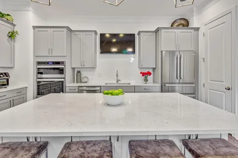 a kitchen view with stainless steel appliances kitchen island granite countertop a refrigerator and a stove top oven