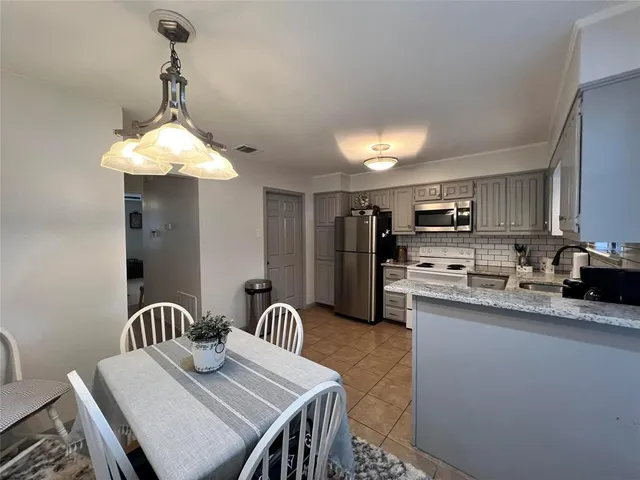 a kitchen with stainless steel appliances granite countertop a sink dishwasher a stove a refrigerator with a dining table and chairs