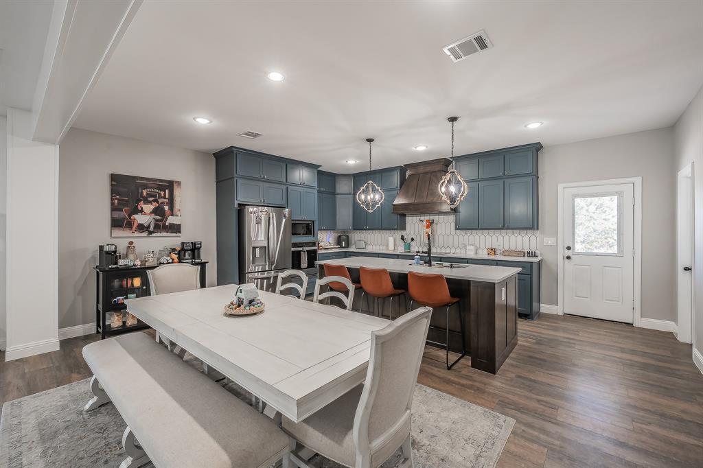 117 Rock Salt Drive Springtown, TX 76082 - Photo 12 of 38 Spacious kitchen featuring deep blue cabinetry, stainless steel appliances, a large island with seating, and wood-finish flooring