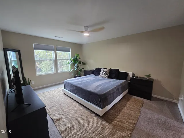 a bed sitting in a spacious bedroom next to a window