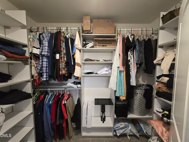 a view of walk in closet with clothes and shoes