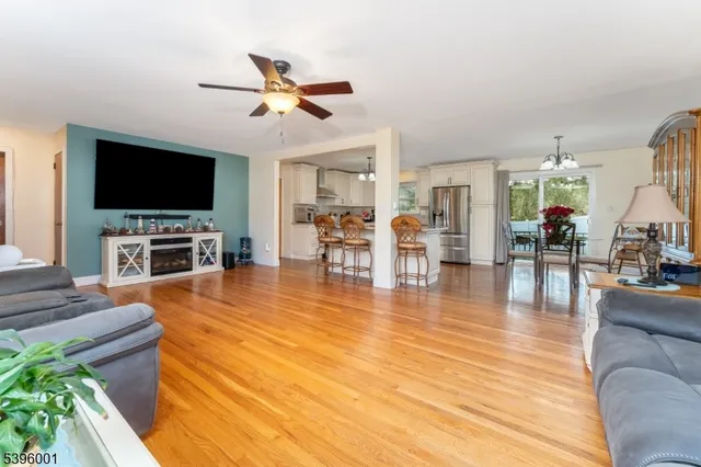 an empty room with wooden floor chandelier fan and windows