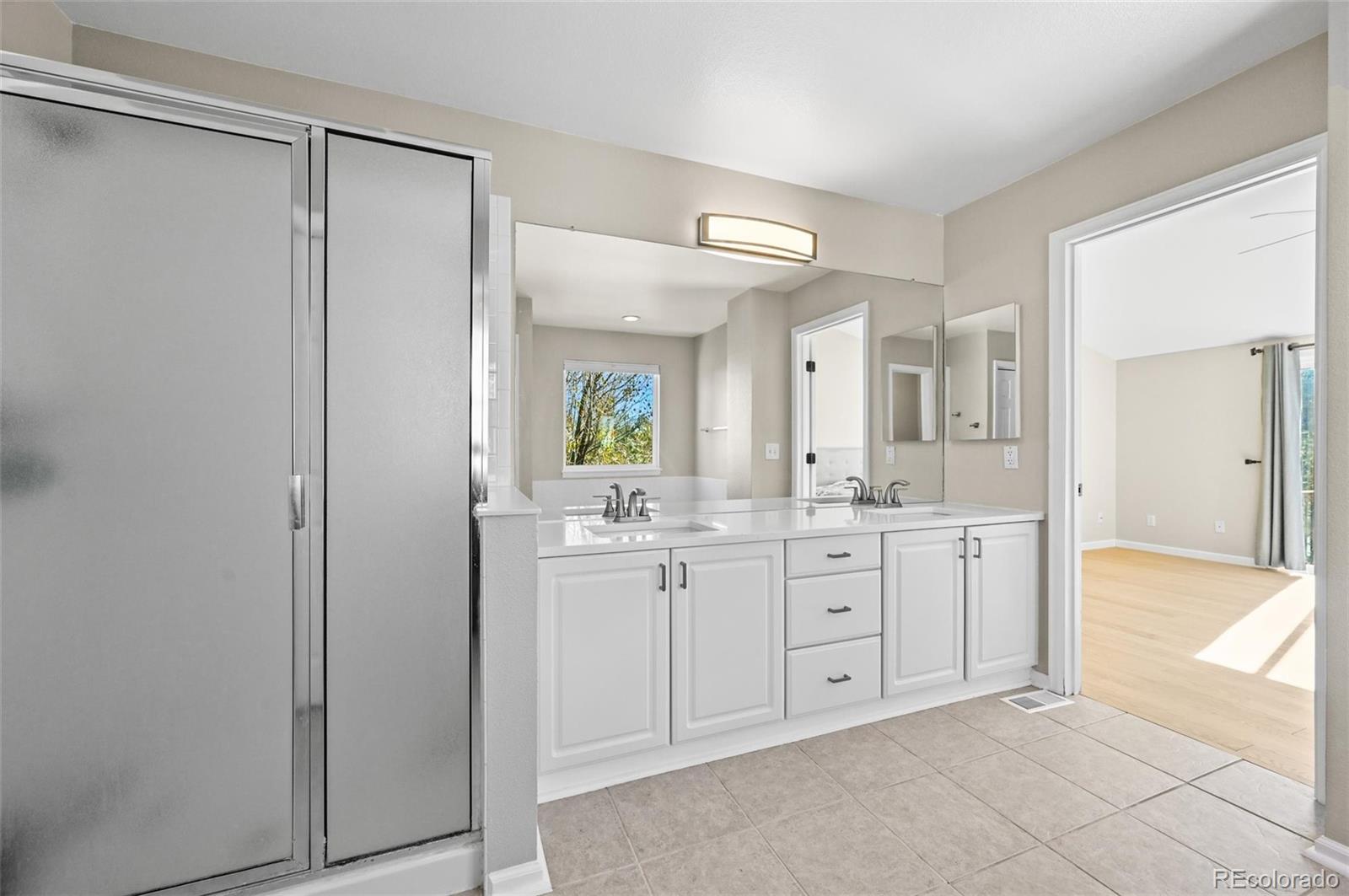 10096 Hughes Place Highlands Ranch, CO 80126 - Photo 23 of 50 a spacious bathroom with a granite countertop sink mirror and a