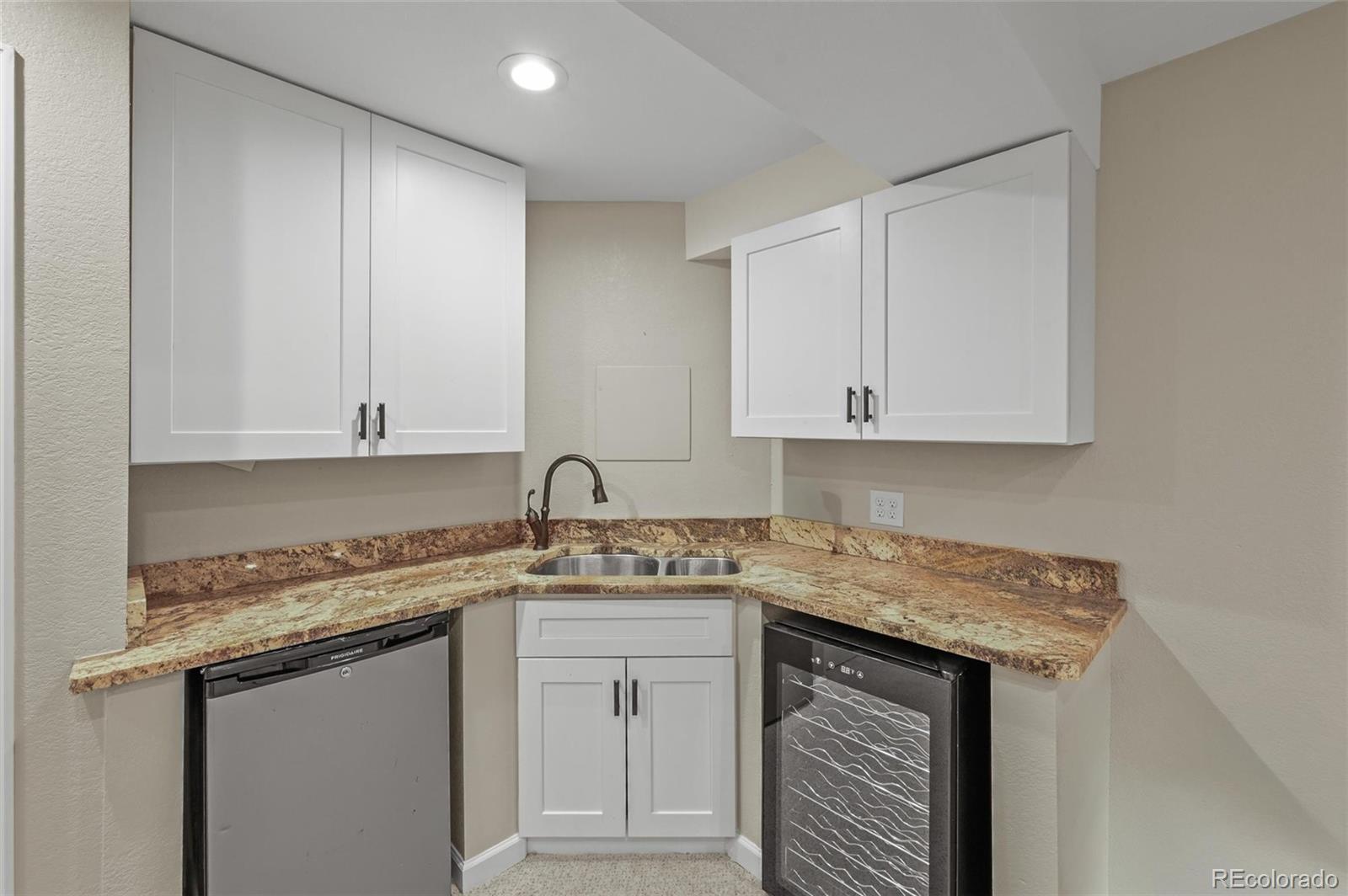 10096 Hughes Place Highlands Ranch, CO 80126 - Photo 36 of 50 a kitchen with stainless steel appliances granite countertop a sink dishwasher a stove and white cabinets with wooden floor