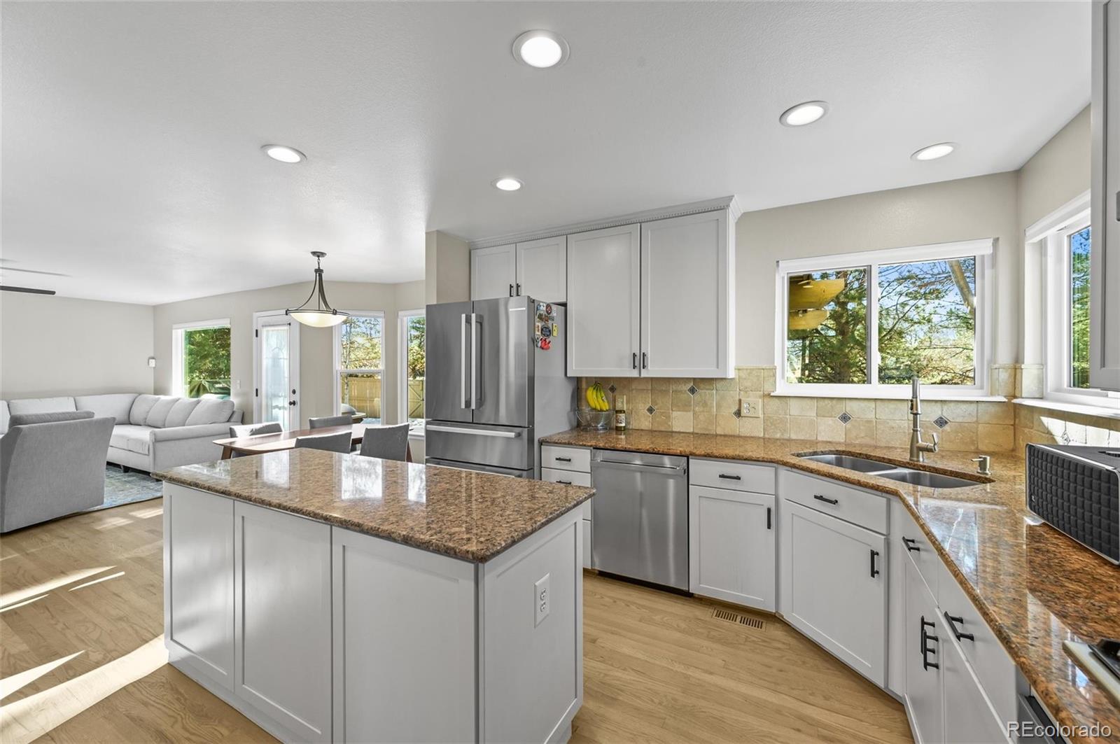 10096 Hughes Place Highlands Ranch, CO 80126 - Photo 6 of 50 a large kitchen with granite countertop a sink and dishwasher with a large window