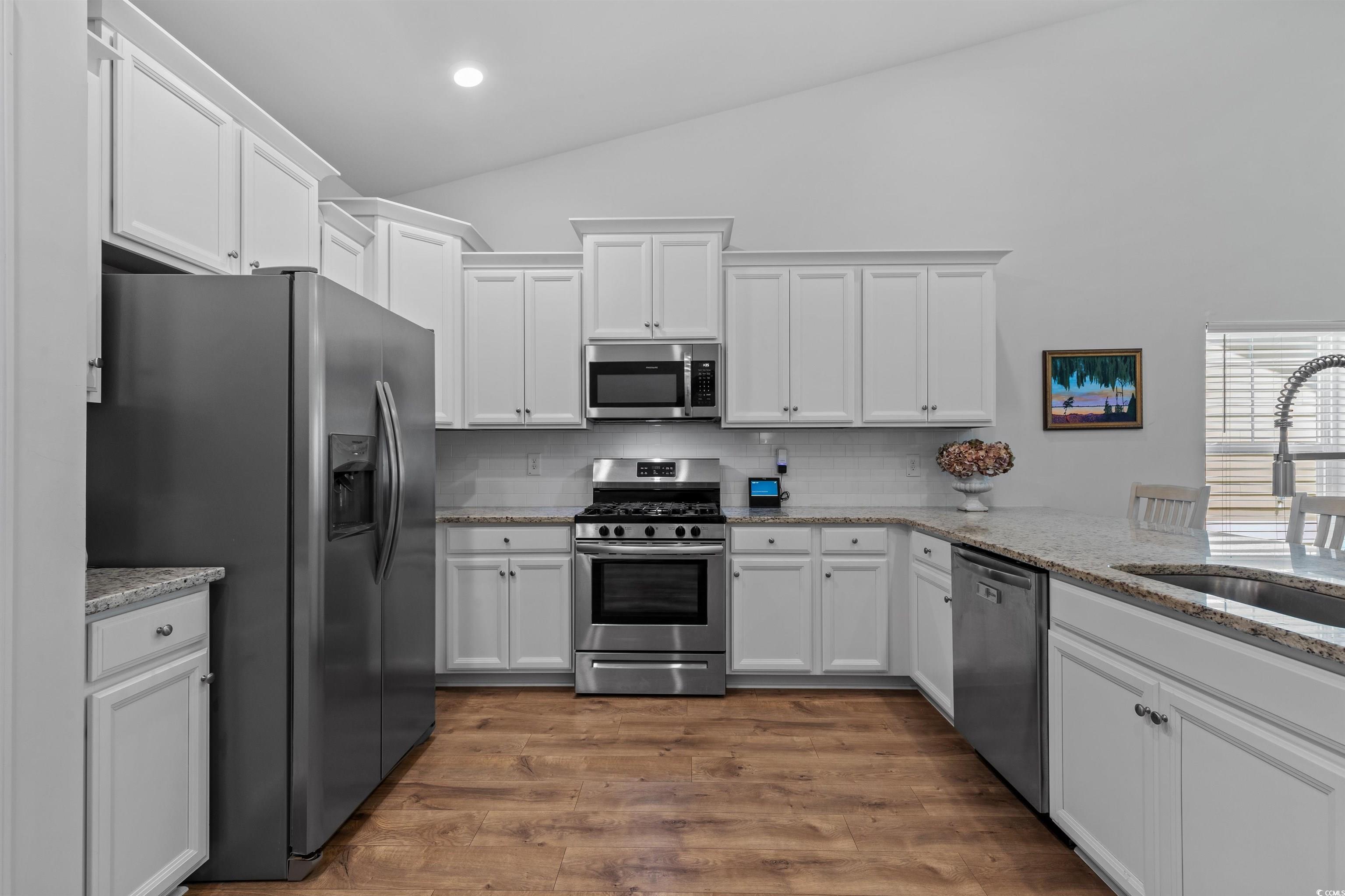 2464 Rock Dove Road Myrtle Beach, SC 29577 - Photo 10 of 34 Kitchen featuring appliances with stainless steel finishes, a sink, white cabinetry, tasteful backsplash, and vaulted ceiling