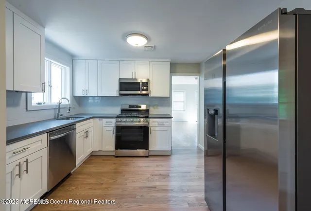a kitchen with granite countertop white cabinets and stainless steel appliances