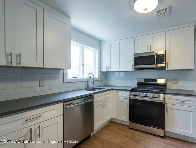 a kitchen with stainless steel appliances granite countertop a stove a sink and a microwave