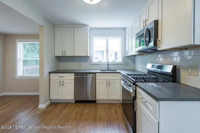 a kitchen with stainless steel appliances granite countertop a stove a sink and a microwave