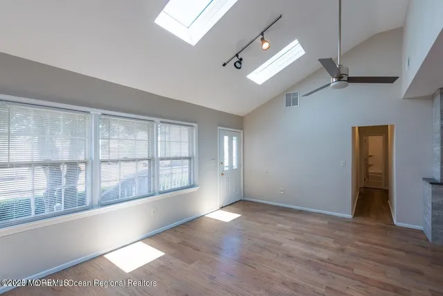 an empty room with wooden floor ceiling fan and windows