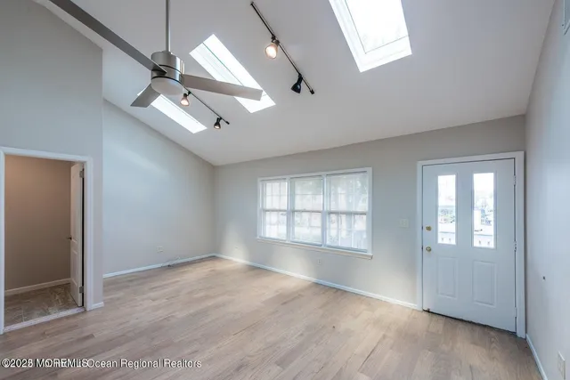 an empty room with wooden floor and windows
