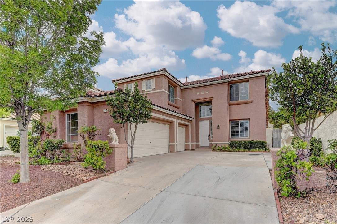 1813 Snow Spring Lane Las Vegas, NV 89134 - Photo 2 of 37 A terracotta-hued facade with twin garage doors and a prominent entry welcomes guests.