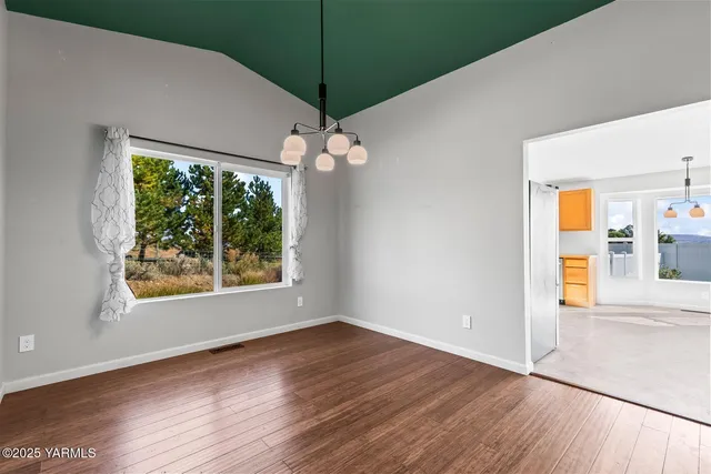 an empty room with wooden floor fan and window