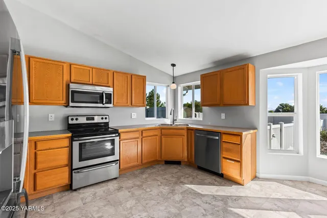 a kitchen with stainless steel appliances granite countertop a stove top oven a sink dishwasher a dining table and chairs with wooden floor