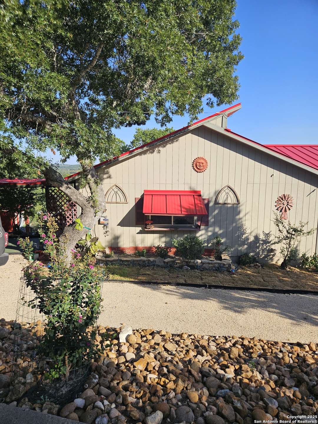 a front view of a house with a yard and a lot of flower plant in front of door