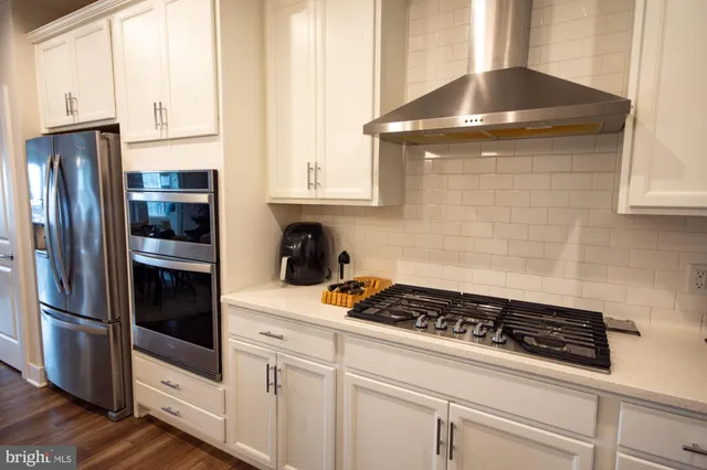 a kitchen with stainless steel appliances granite countertop a refrigerator and a stove