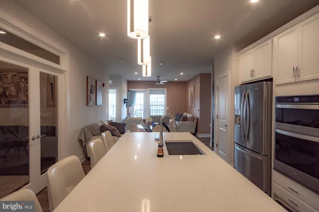 a large kitchen with stainless steel appliances a refrigerator a sink a stove a dining table and chairs