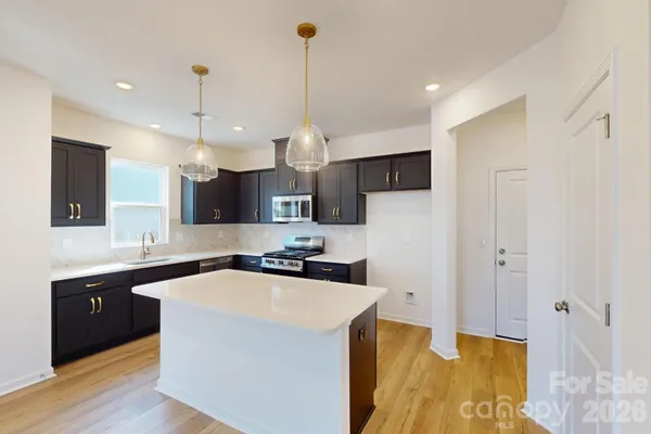 a kitchen with stainless steel appliances granite countertop a sink a stove and a refrigerator