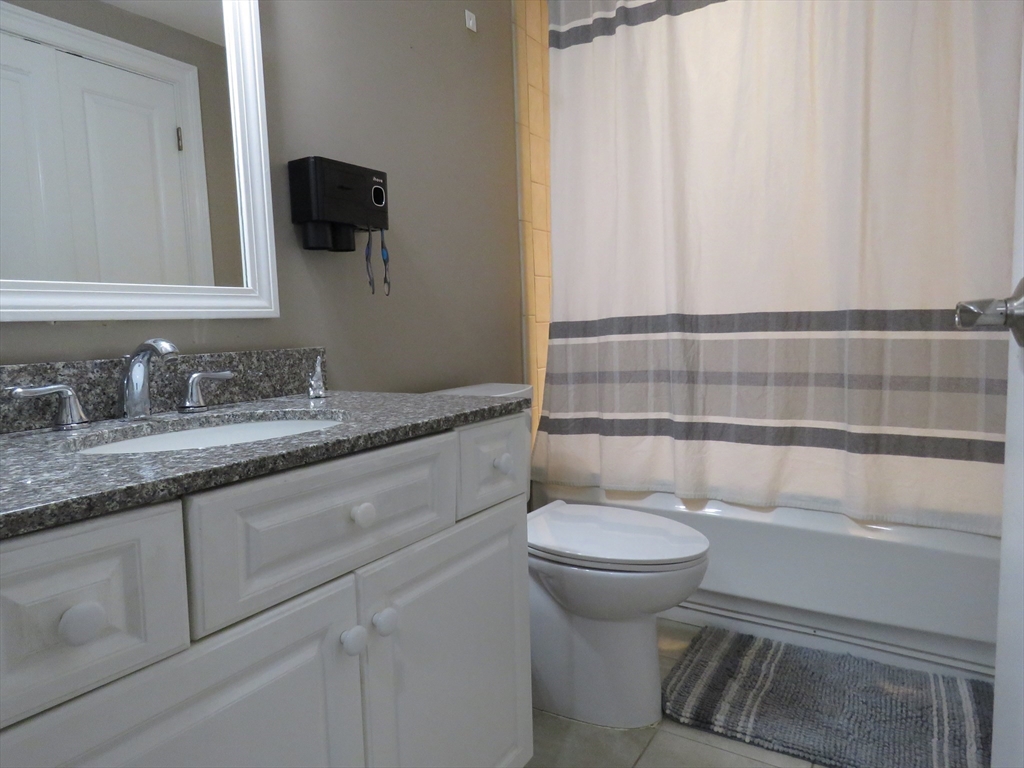 61 Market Street, Unit 2B Lowell, MA 01852 - Photo 13 of 20 a bathroom with a granite countertop toilet sink and mirror