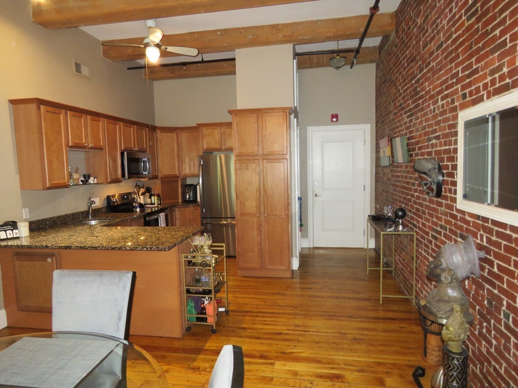 61 Market Street, Unit 2B Lowell, MA 01852 - Photo 7 of 20 a kitchen with stainless steel appliances granite countertop a refrigerator stove microwave and sink
