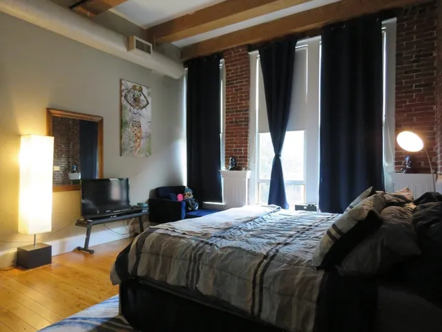 a bedroom with a bed and large windows