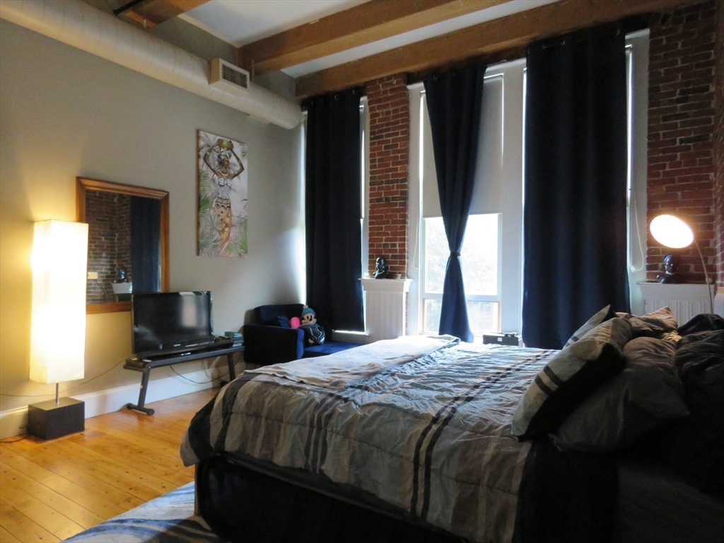 61 Market Street, Unit 2B Lowell, MA 01852 - Photo 10 of 20 a bedroom with a bed and large windows