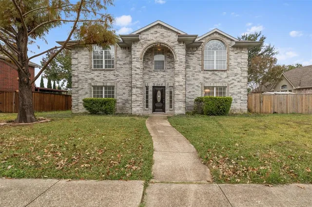 a view of a brick house with a yard and large tree