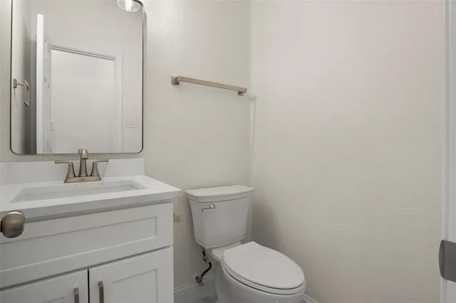 a bathroom with a toilet sink vanity and mirror