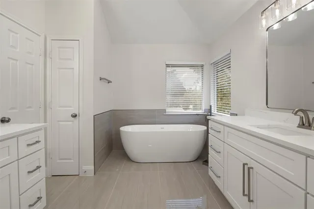 a spacious bathroom with a tub sink and mirror