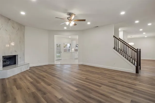 a view of an empty room with wooden floor and a kitchen